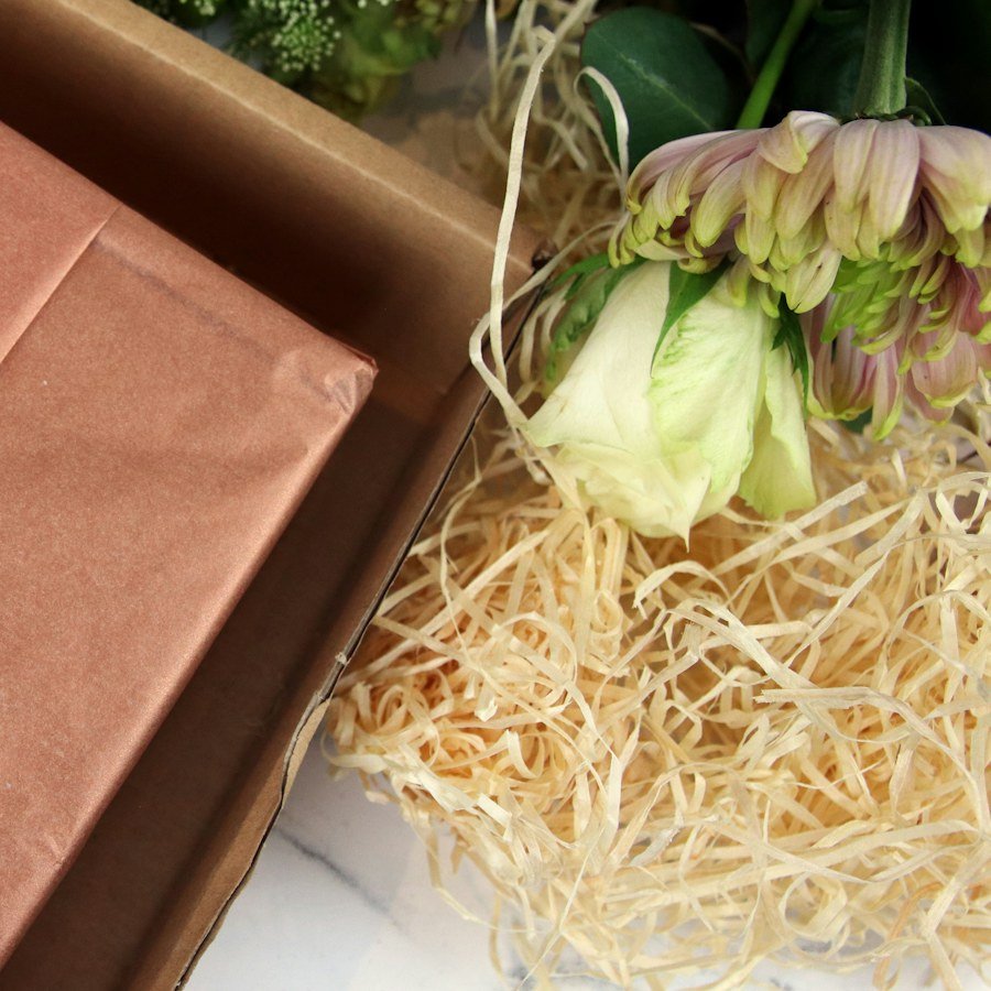 Un colis emballé de papier kraft, avec des fleurs et de la paille